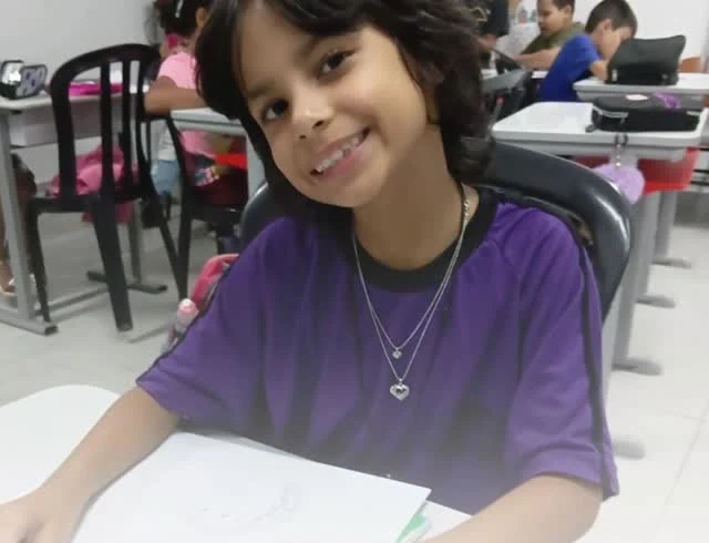 Criança desenha em mesa durante atividade OPNI Mirim